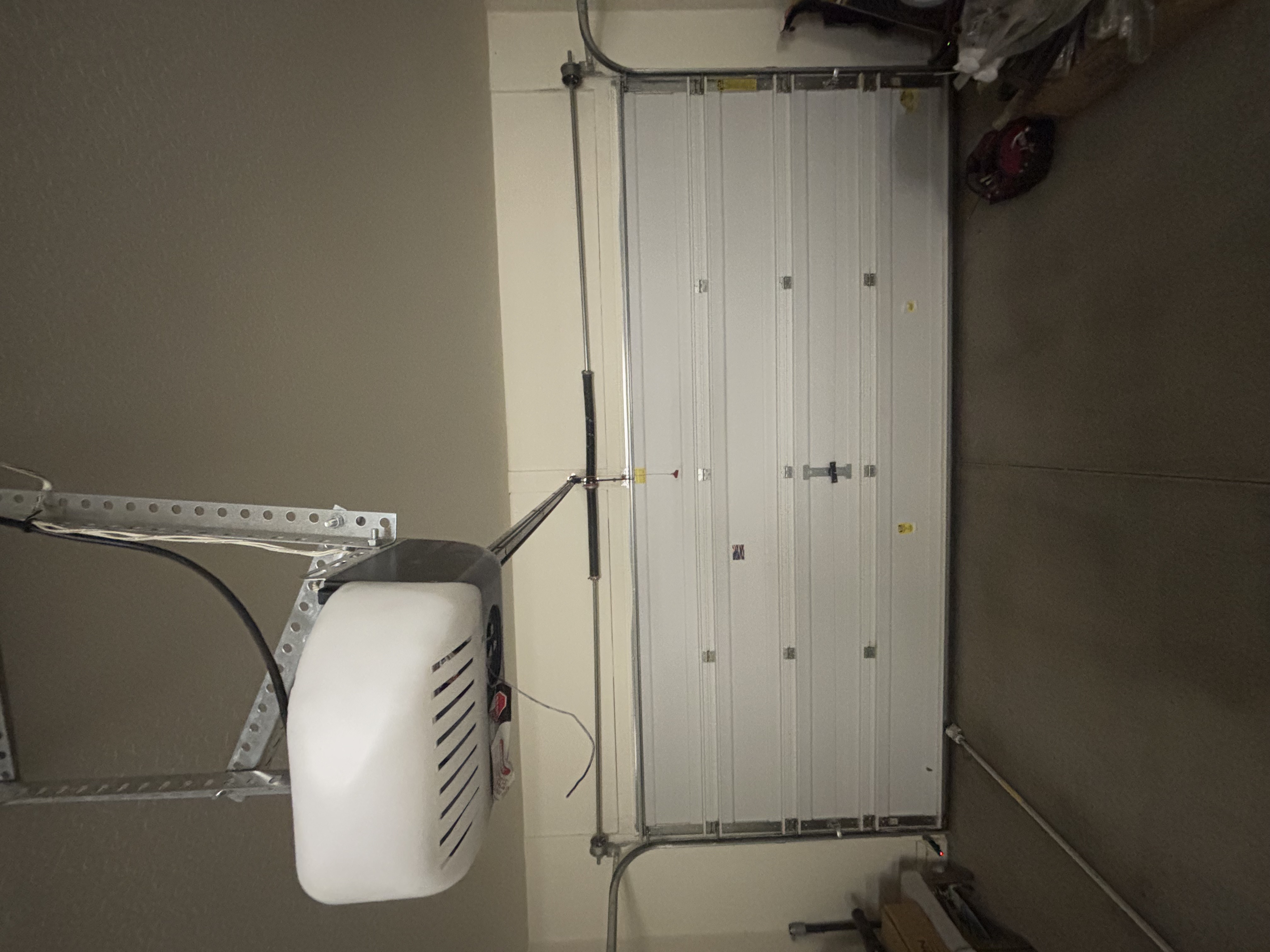 Technician's ladder and tools set up during a garage door opener service call.